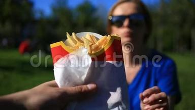 一男一女在街上吃快餐。她从他手里接过薯条吃了。反对
