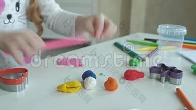 一个小女孩玩橡皮泥，用手把它<strong>卷起</strong>来，桌面上有数字和彩色铅笔