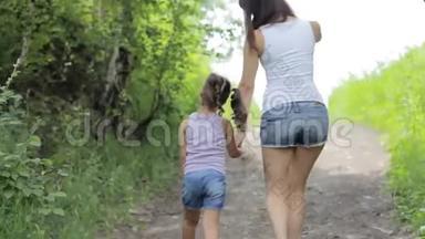 家庭<strong>价值观</strong>。 年轻的妈妈牵着小女孩的手在公园散步。 后退。