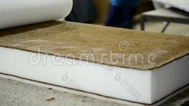 床垫制造厂的工人在工厂特写上用胶水覆盖基本的椰子层。