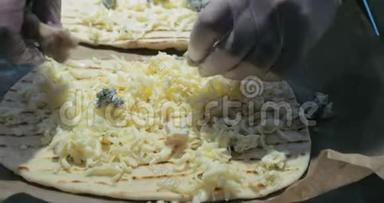 戴乳胶手套的厨师在烤盘上展示比萨饼的面团，在面团上展示不同的奶酪，面团在纸上传播