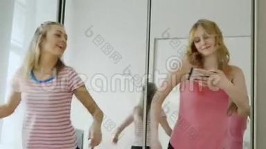 两个有趣的少女在卧室里跳舞。 重复舞蹈动作，<strong>看手机</strong>屏幕。 帕贾马党