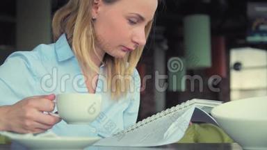现代<strong>女孩</strong>在咖啡馆<strong>喝茶</strong>，使用平板电脑和写在笔记本。 在咖啡店工作的漂亮<strong>女孩</strong>