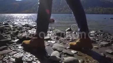 阿尔泰。 两个视频合一.. 露营妇女坐在山湖畔.. 穿着登山靴的女孩的脚