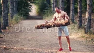 强壮强壮的男人<strong>在</strong>森林道路上举起一根木头