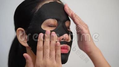 年轻女子做带净化面膜的黑色面膜