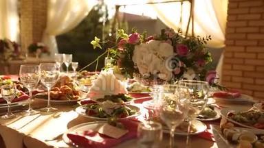 婚礼桌乡村风格的装饰与菜肴，饮料和花的粉红色和米色。 各种植物组成