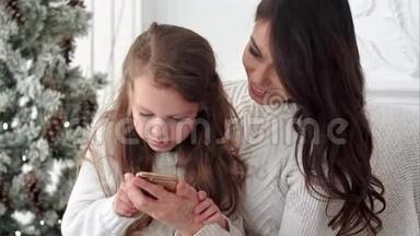 年轻的母亲教女儿如何在圣诞<strong>节</strong>装饰的房间里使用智能<strong>手机</strong>