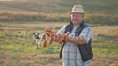 快乐的成年农夫微笑着看着镜头，手里拿着香肠，手里拿着一群奶牛在农场的牛棚里。 农业