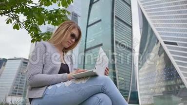 一个金发<strong>女孩</strong>在市中心和高楼的背景下<strong>使用</strong>白色笔记本电脑。 戴太阳镜的<strong>女孩</strong>。