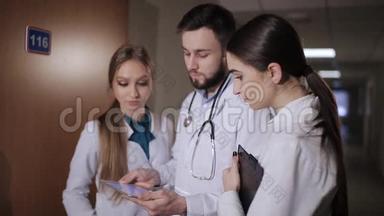 医生在医院走廊实习生解释说，病人接受。 医生和两个女实习生分析诊断