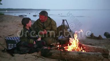 父子俩<strong>围坐</strong>在湖边的篝火旁..