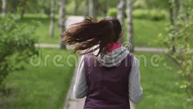 跑步女孩。 一位年轻的<strong>运动</strong>员穿过夏季公园，从后面看。 <strong>摄像机</strong>跟随模型。 慢慢