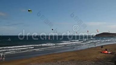 许多五颜六色的风筝在海滩上和风筝冲浪在大<strong>风天</strong>乘风破浪