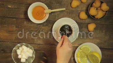 女人用茶在木桌上的白色杯子里用勺子搅拌