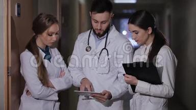 医生在医院走廊实习生解释说，病人接受。 医生和两个女实习生分析诊断