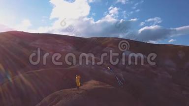 空中：一个年轻的女孩站在红山，在高山上放风筝。 自由的思想，