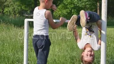 家庭运动。小男孩和小女孩在足球场上做运动，在单杠上做运动