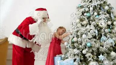 圣诞老人帮助漂亮的小女孩装饰圣诞树