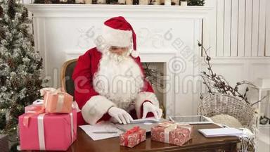 忙碌的圣诞老人正坐在他的桌子上查看圣诞信件