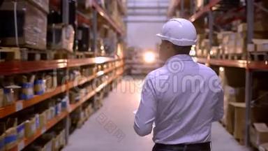 员工男仓库工人工程师戴安全帽在施工现场仓库工作，在物流中行走