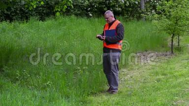 园林经理在智能手机上拍照，靠近劣质割草机