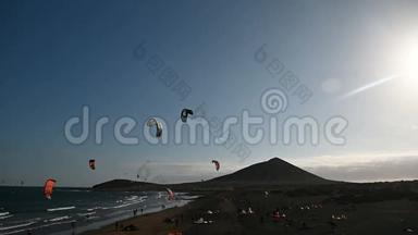许多五颜六色的风筝在海滩上和风筝冲浪在大风天乘风破浪
