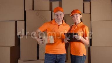 穿着橙色制服的<strong>快递</strong>员站在棕色纸箱堆后面。 <strong>快递</strong>公司的员工。 4K工作室视频