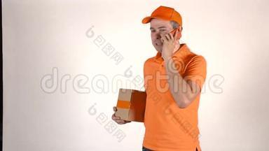 穿着橙色制服的英俊的快递员在他的手机上交谈，送了一个包裹。 浅灰色背景，4K演播室