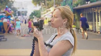 一个职业<strong>摄影</strong>师在<strong>游乐园</strong>拍照，一个女人在开花间按下一个小玩意的按钮