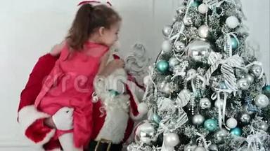 假圣诞老人装饰圣诞树抱着一个小女孩的胳膊