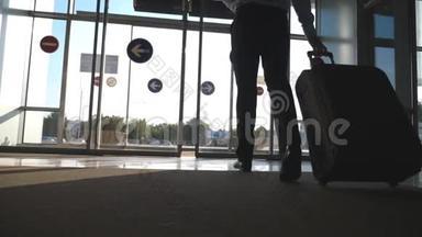 商人带着行李从机场走出来。 一个人穿过玻璃自动门来到大街上翻滚