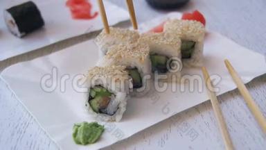 筷子从盘子里取出寿司卷，在日本餐馆里蘸酱油。 慢动作