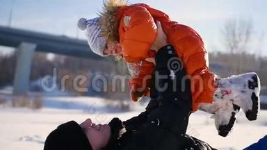 男人在阳光明媚的冬天和你的孩子玩。 抱在<strong>怀里</strong>.. 冬季景观