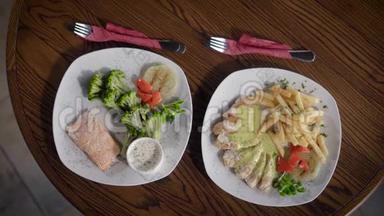 从餐厅看到的盘子和食物的顶部，它们站在一张木桌上。 盘子上放着一条鱼