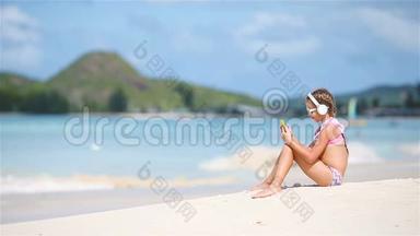 小女孩在海滩上用耳机听音乐