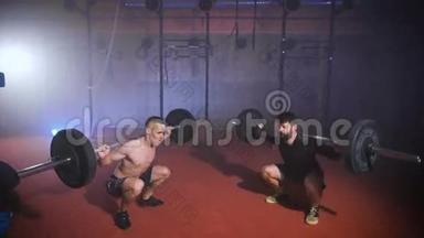 两个强壮的男人一起在健身房做举重训练。