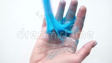 女孩把蓝色的<strong>黏液</strong>伸到两边。 女人的手在玩<strong>黏液</strong>玩具。 在白色上做<strong>黏液</strong>。 时髦的液体玩具棒