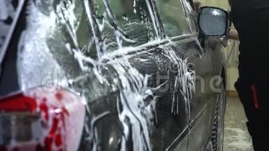 洗车一个洗车工洗车.. 一个男人用泡沫海绵洗汽车。 特写镜头。 慢动作。