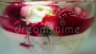 女人在玻璃里用勺子吃冰淇淋和樱桃