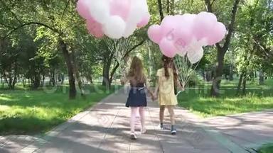 孩子们拿着气球穿过夏天的公园。 两个小女孩拿着很多五颜六色的气球。 从
