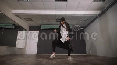 空工作室里的女人上舞蹈课。 她穿着一件免费的衬衫，头上戴着一顶帽子