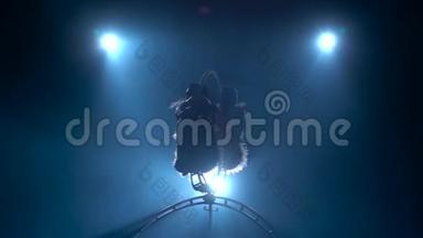 女孩空中杂技演员在空中旋转的金属箍。 黑烟背景。 <strong>剪影</strong>。 慢<strong>动作</strong>