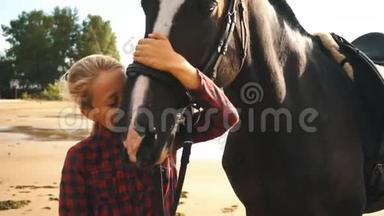 美丽的女孩在海滩上照顾她的马。 把注意力集中在女孩身上。