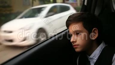 少年坐在车里<strong>看着窗外</strong>。 <strong>窗外</strong>闪烁<strong>着</strong>城市的树木和房屋