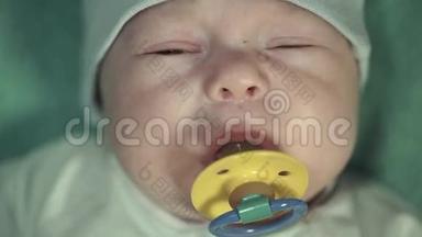 一个刚出生的小男孩的肖像，穿着温和的绿色西装，带着一个黄色的奶嘴。