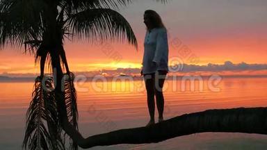 一个女孩站在海滩上<strong>红日</strong>落的<strong>背景</strong>下的棕榈树上