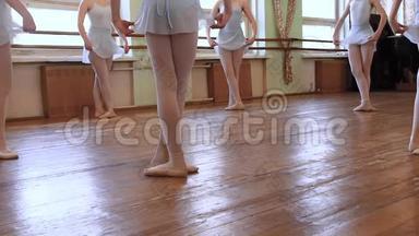穿着蓝色芭蕾舞服的女孩站在第三个位置，开始在磨损的芭蕾舞教室的地板上围成圆圈跳舞。 高清高清