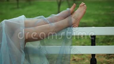 赤脚的女孩穿着<strong>蓝色</strong>裙子，躺在长凳上，移动脚趾，在照片<strong>会议</strong>。