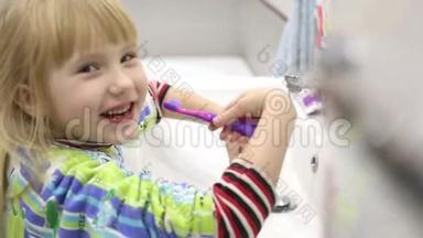 小女孩正在刷牙，然后用毛巾擦脸和手，然后离开框架。